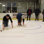 Ryan Hand (left) and Eric McLaughlin draw curling targets on the ice at the Morgantown Ice Arena Saturday night in preparation for the Morgantown Curling Club’s “Learn to Curl” event as other members of the club look on.